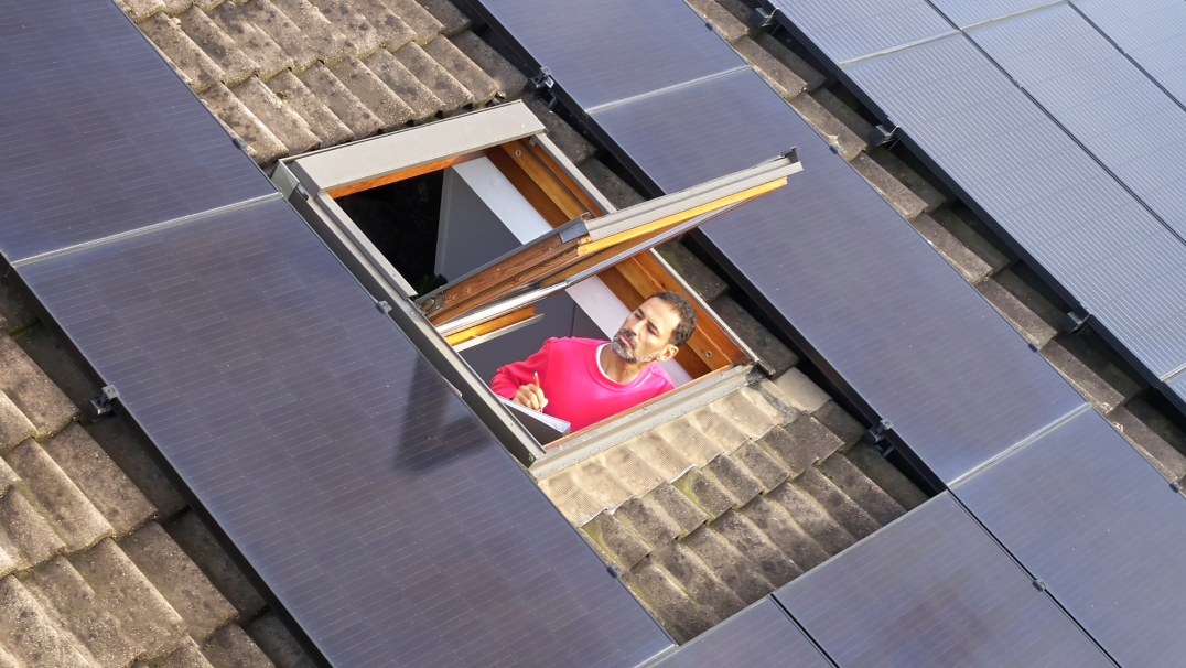 Monteur in dakraam met zonnepanelen op dak